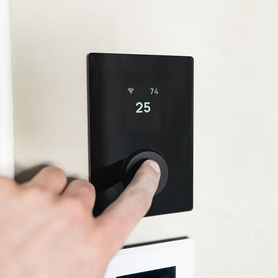 Main réglant un thermostat connecté mural